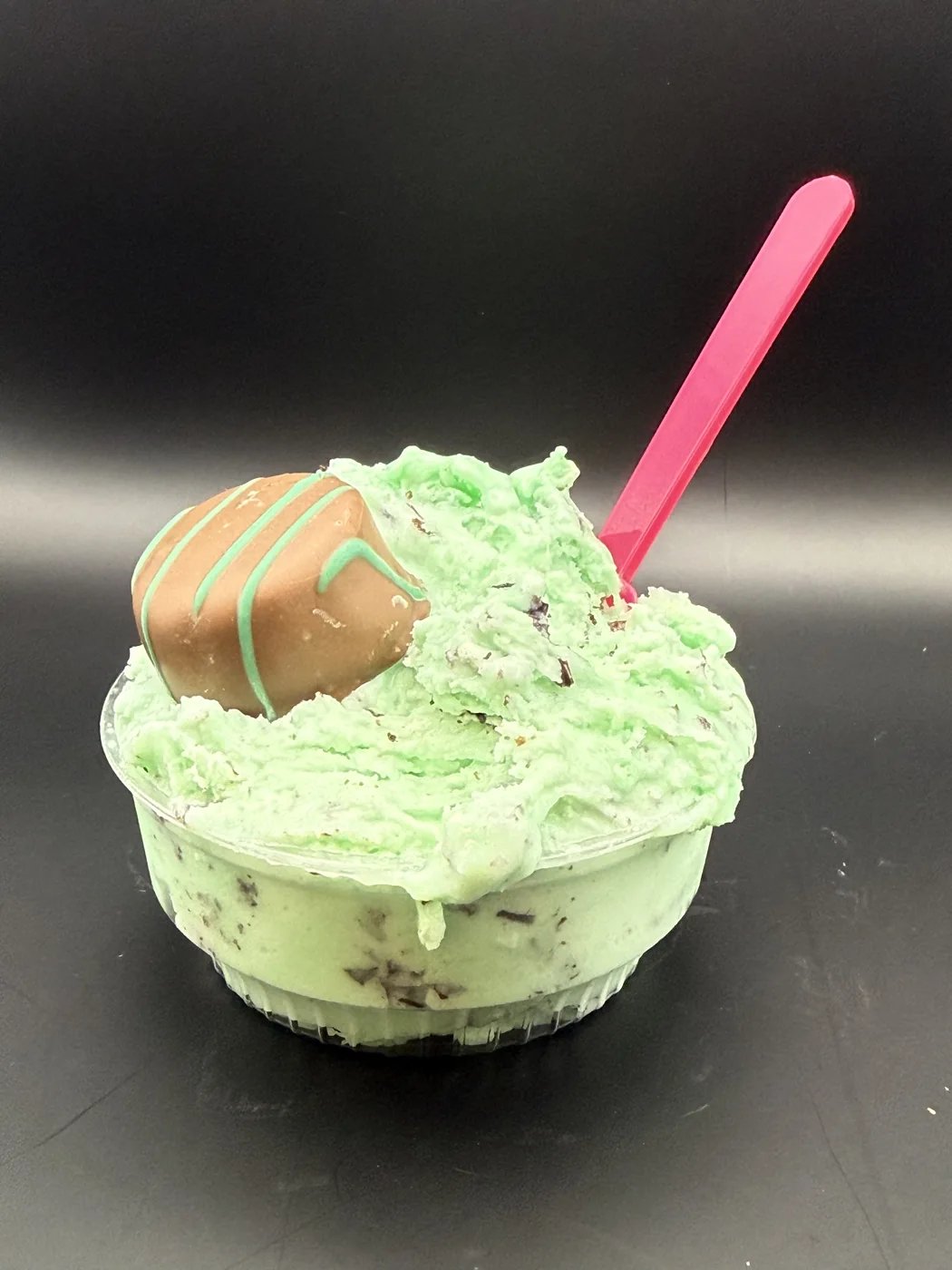 A cup of mint chip gelato with a chocolate confection on top